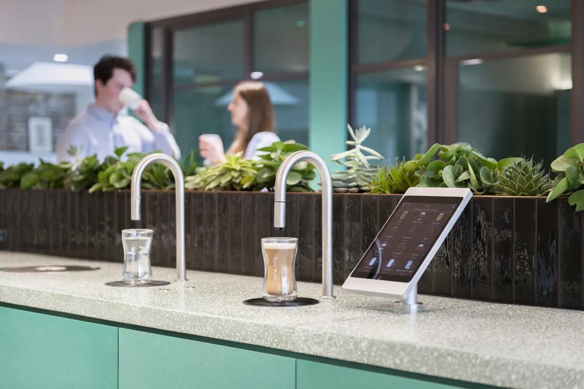 Image showing a TopBrewer commercial coffee machine and TopWater water dispenser with two people chatting in the background