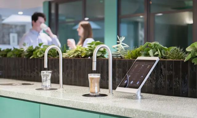 Image showing a TopBrewer commercial coffee machine and TopWater water dispenser with two people chatting in the background